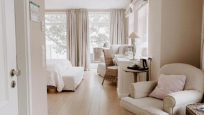 Une chambre d’hôtel avec un lit, une chaise, une table avec une lampe et une vue sur les arbres à l’extérieur.