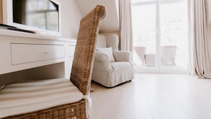 A modern, minimalist room with a television, wicker furniture, a sofa, and a large window with curtains.