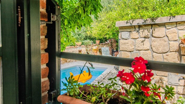 Ein Balkon mit Blick auf ein Schwimmbecken, Blumentöpfen und eine Steinmauer.