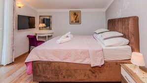 Ein Schlafzimmer mit einem Bett, einem Schreibtisch, einem Sessel, einem Fernseher und einem Bild an der Wand.