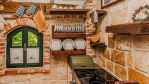 Eine rustikale Küche mit Backsteinwand, Holzböden und einem grünen Fenster.