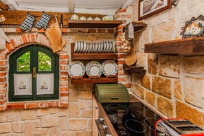 A rustic kitchen with a brick wall, wooden shelves, and a green window. - Charming Holiday Home in Maslenica (Jasenice)