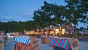 Beach chairs with numbers, a building with lights, and trees in the background.
