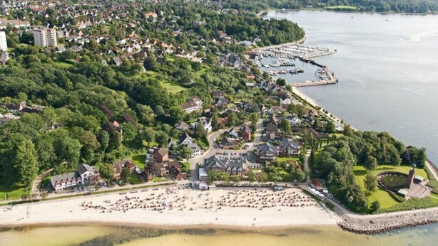 An aerial view of a coastal town with a beach, residential area, and marina.