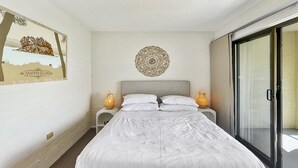 Een slaapkamer met een bed, een decoratief object aan de muur en een schuifglazen deur.