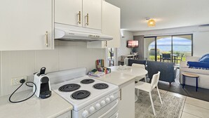 Een compact keuken met een fornuis, een broodrooster en een klein eethoekje met een tafel en stoelen.