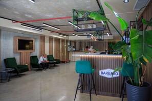 A bar area with a sign reading "Caffè BARBATO Napoli," green chairs, and a large potted plant. - Modern oasis in Batumi - minimalist style with maximum comfort (Batumi)