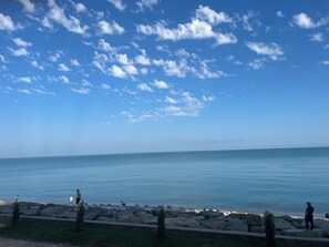 Une vue sur la côte, avec un ciel dégagé, une mer calme et un rivage rocheux parsemé de chaises longues.