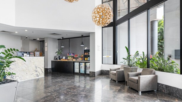 Un'ampia hall con una reception in marmo, area salotto e grandi finestre che offrono vista all'esterno.