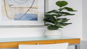 Una scrivania con una pianta in vaso, un quadro astratto incorniciato e una sedia.