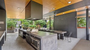 Uma cozinha moderna com ilha central, forno embutido e vista para o jardim.