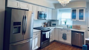 A modern kitchen with stainless steel appliances, white cabinetry, a built-in oven, microwave, and a dishwasher.