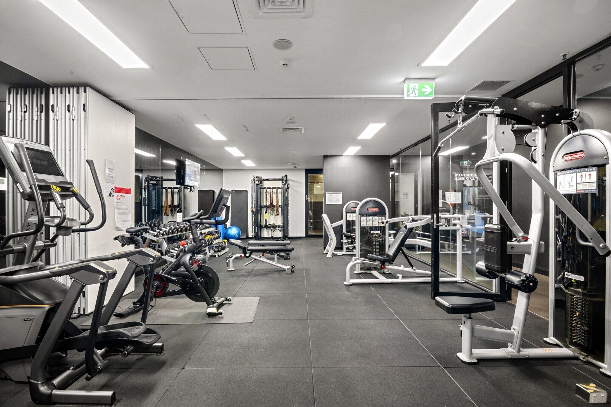 A modern gym with various exercise equipment, including treadmills, weight machines, and free weights.