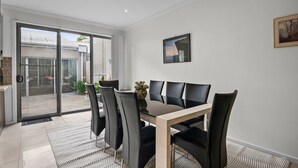 Uma sala de jantar moderna com uma porta de vidro que dá para um pátio, uma mesa de madeira e cadeiras pretas.