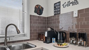 Uma cozinha moderna com uma pia de aço inoxidável, uma cafeteira e uma torradeira.