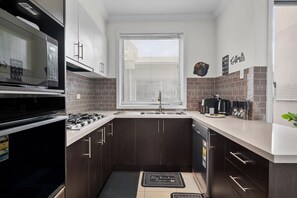 A compact kitchen with dark wooden cabinets, a stainless steel sink, and a microwave.