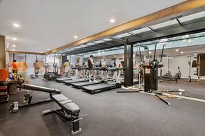 A modern gym with treadmills, weight machines, and a bench. - 2-Bed High-Rise Apartment with Pool & Gym (Melbourne)