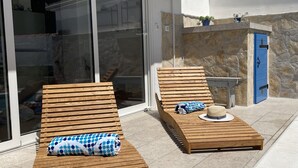 A poolside area with two wooden loungers, a stone wall, and a blue door. - Holiday Home Cherry With Pool (Marina)