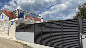 A modern house with a balcony, a stone wall, and a metal fence. - Holiday Home Cherry With Pool (Marina)