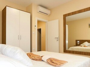 Ein Hotelzimmer mit Bett, Kleiderschrank, Spiegel und Klimaanlage.