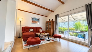 A living room with a sofa, ottoman, coffee table, and a painting on the wall. - Air-conditioned villa with a private pool, sleeps 7, in Saint-Paul-en-Forêt (Saint-Paul-en-Forêt)