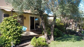 Ein Haus mit einer Terrasse, Sitzgelegenheiten im Freien und einem Garten.