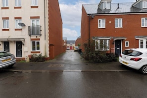 A narrow residential street with two-story houses, parked cars, and a visible satellite dish on one of the buildings. - Charming 5-bedroom Townhouse in Central Gloucester (Gloucester)