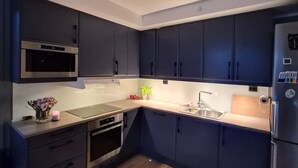 Een moderne keuken met donkere kastjes, roestvrijstalen apparatuur en een houten vloer.