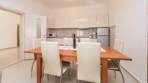 Una cocina moderna con armarios blancos, una mesa de comedor de madera y cuatro sillas.