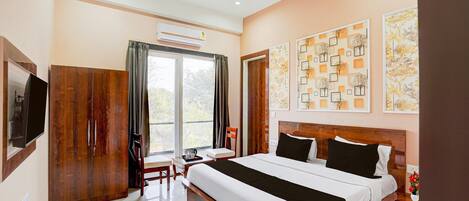 Una habitación de hotel con una cama grande, un escritorio con una silla, un televisor y obras de arte en las paredes.