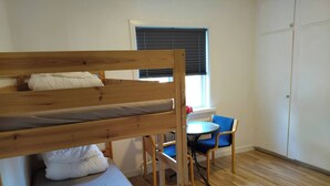 A bunk bed with a lower bunk, a small table with a chair, and a window with blinds. - Family-friendly Apartment Retreat in Dalarna Sweden (Orsa)