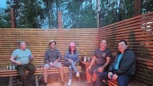 Four people seated on wooden benches around a campfire. - Family-friendly Apartment Retreat in Dalarna Sweden (Orsa)