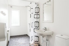A bathroom with a white sink, a toilet, a shower curtain with a geometric pattern, a window, and a mirror. - Family-friendly Apartment Retreat in Dalarna Sweden (Orsa)