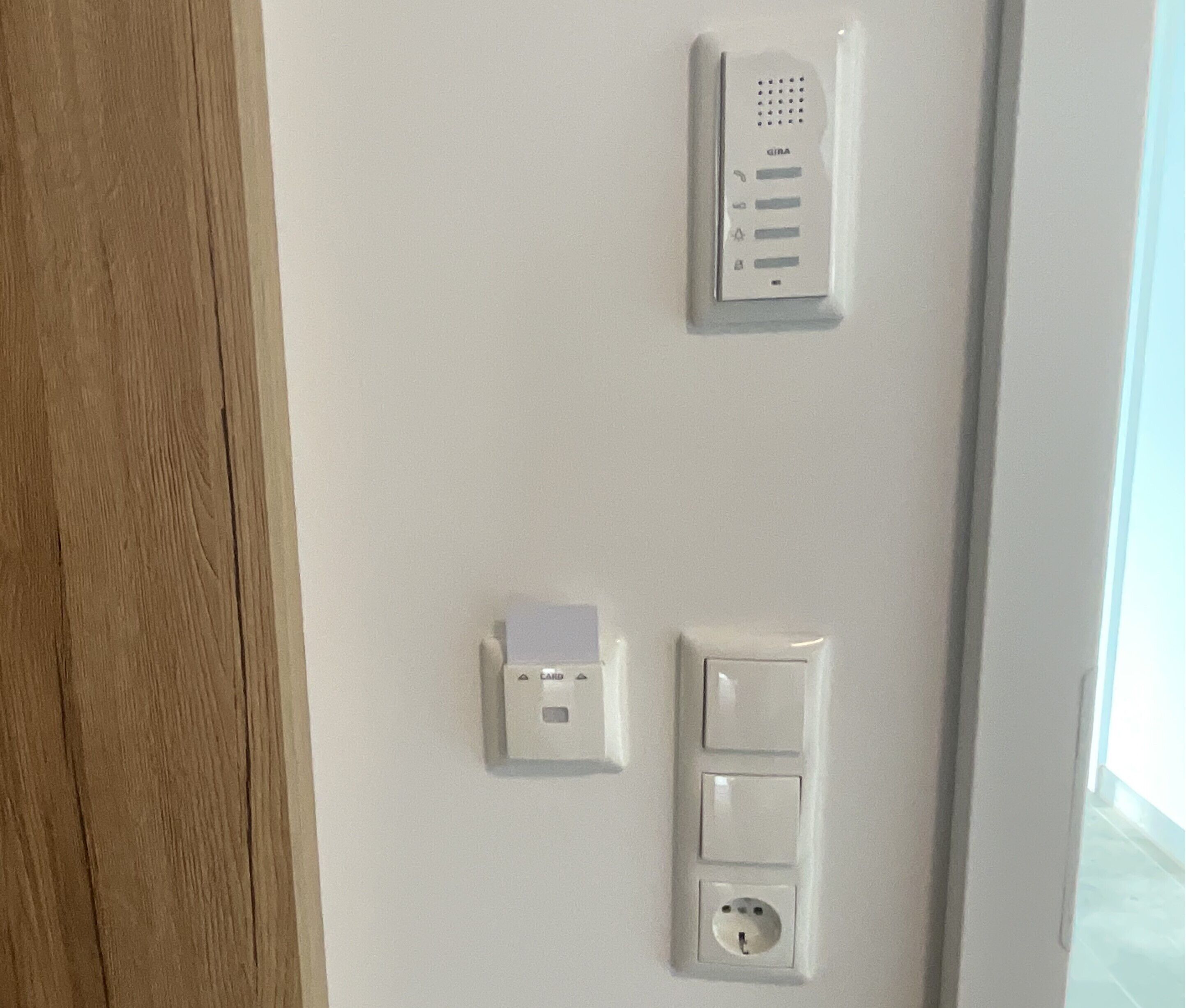 Un mur muni d’un interphone GIRA, d’un lecteur de cartes et d’une prise de courant.