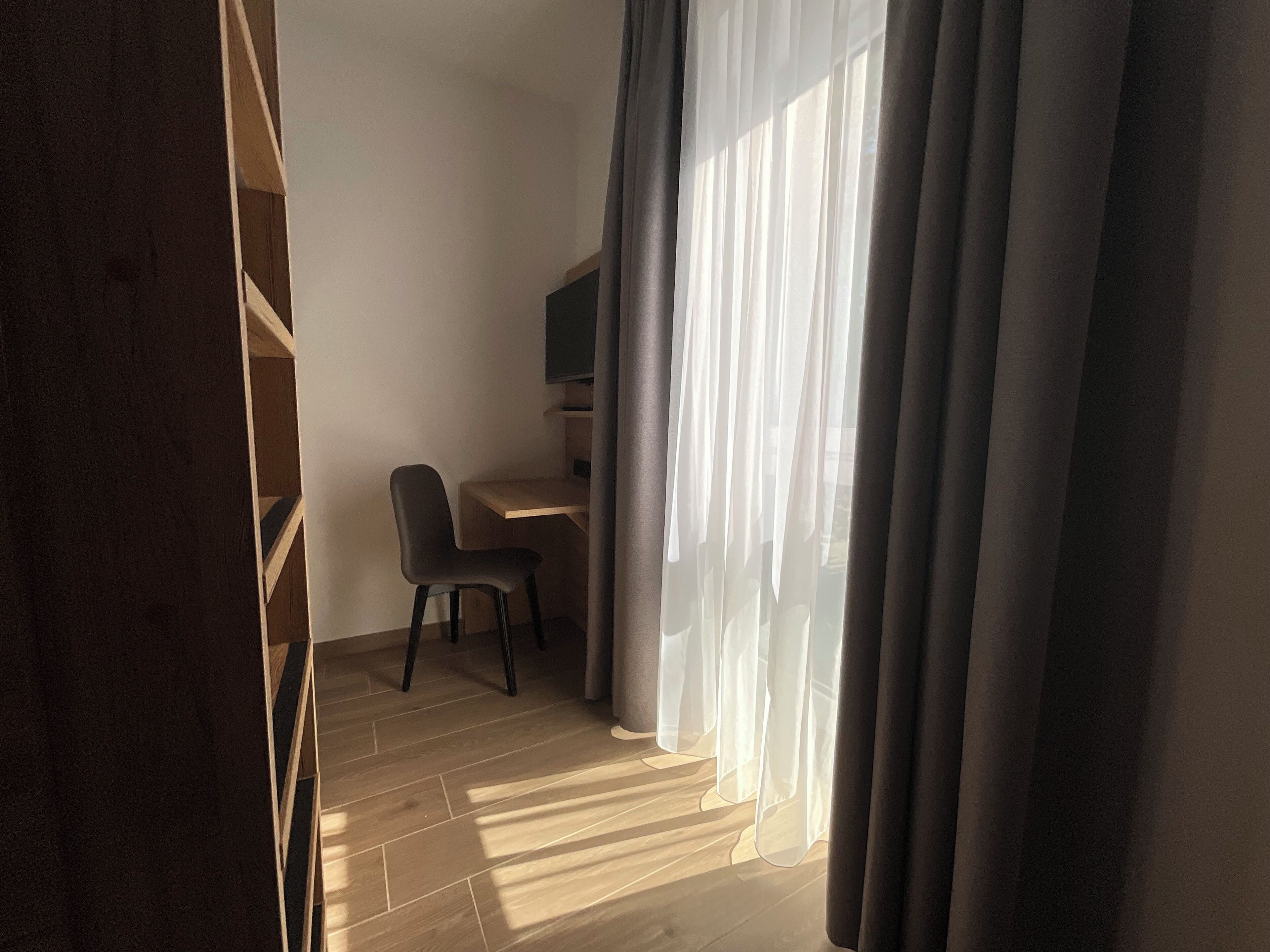 Ein Zimmer mit einem Holztisch, einem Stuhl und einem Fernseher.