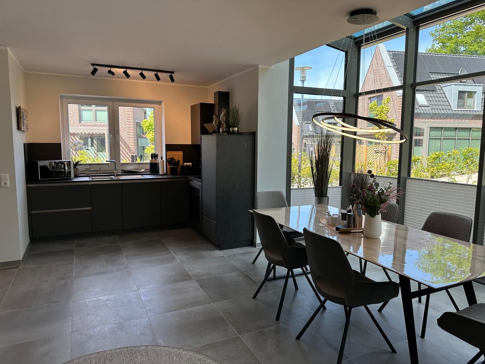 A modern kitchen with a dining area, large windows, and a view of the outside.