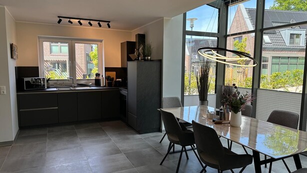 A modern kitchen with a dining area, large windows, and a view of the outside. - Moin and welcome to the vacation home "achtern diek" (Dangast)
