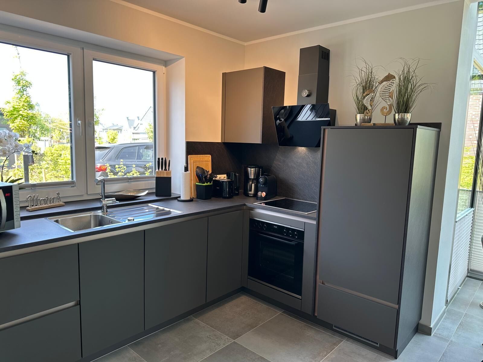 A modern kitchen with a built-in oven, a sink, and a refrigerator.