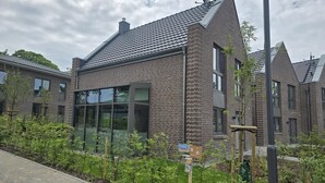 A modern building with a brick facade, large windows, and a sloped roof. - Moin and welcome to the vacation home "achtern diek" (Dangast)