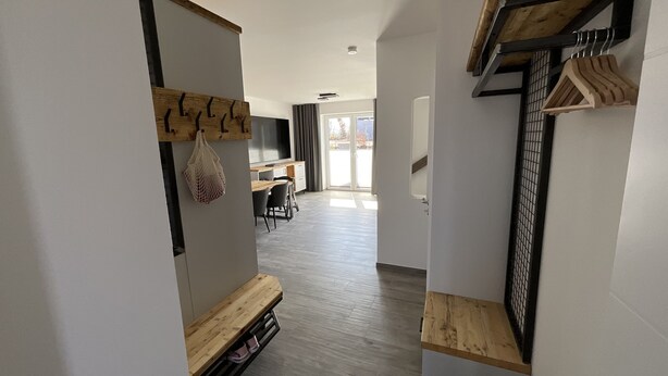Ein modernes Interieur mit einer Holzbank, einem Schuhregal und einem Garderobenschrank.