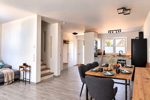 Eine moderne Küche mit Essbereich, Holzboden und einer Treppe zu einer weiteren Ebene.