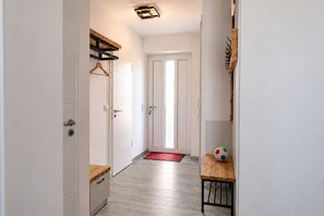 A hallway with white walls, a wooden bench, a red doormat, and a soccer ball on the bench. - Hello and welcome to the Ackerpulko Vacation Home! (Dangast)