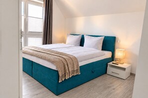 A modern bedroom with a bed, a bedside table, and a lamp. - Hello and welcome to the Ackerpulko Vacation Home! (Dangast)