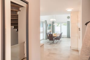 A modern kitchen with white cabinets, a dining area with a table and chairs, and a staircase leading to another level. - Moin and welcome to Ferienhaus Freya! (Dangast)