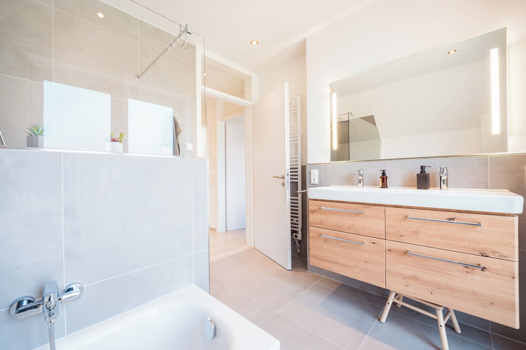 Une salle de bain moderne avec une baignoire, un meuble-lavabo avec un miroir et un espace douche.