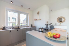 A modern kitchen with a large island, a built-in oven, and a fruit bowl. - Hello and welcome to the Strandheimat! (Dangast)