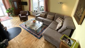 En stue med sofa, lænestol, sofabord i glas og et spisebord.