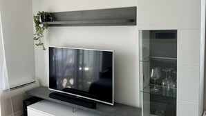 A modern living room with a flat-screen TV, white cabinetry, and a glass coffee table. - Coastal Family Apartment in Zadar (Zadar)