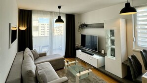A modern living room with a sofa, TV, and glass coffee table. - Coastal Family Apartment in Zadar (Zadar)