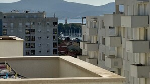 A view of a cityscape with modern buildings, a distant mountain, and a body of water. - Coastal Family Apartment in Zadar (Zadar)